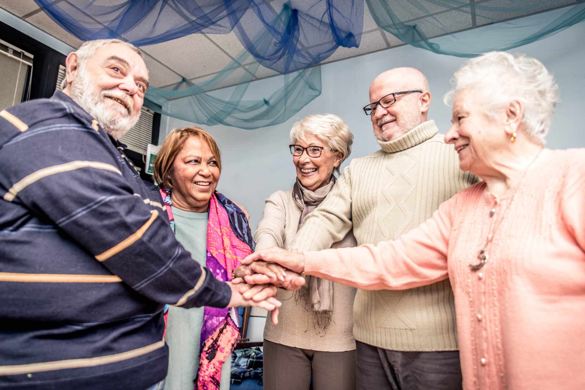 A group of seniors standing in a circle with their hands in the middle